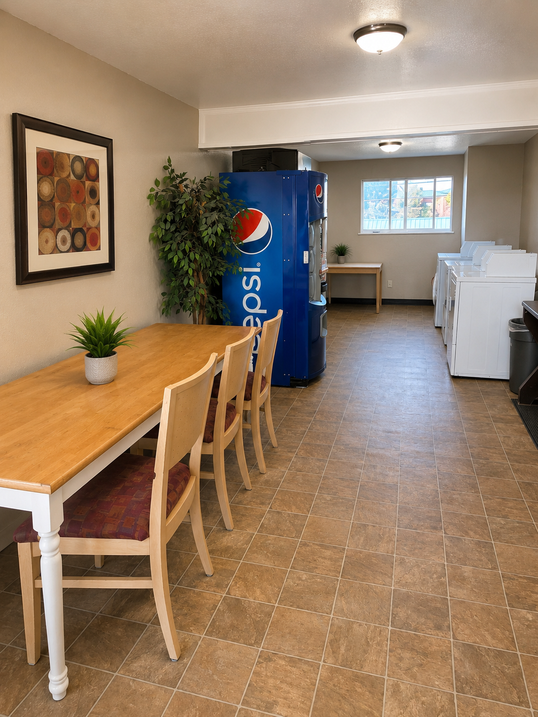On-site laundry room at Sunset Suites with washers, dryers, seating table and vending machine